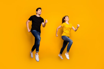 Fototapeta na wymiar Full body photo of sporty guy lady couple jumping high active way of life pair race get to finish line first wear casual jeans black t-shirts isolated yellow color background