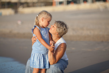 Portrait of happy mother and small daughter. They hug on the background of the sea.