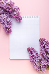 Lilac, cup of coffee, notepad on pink background. Still life. Spring romantic mood. Top view. Copy space - Image