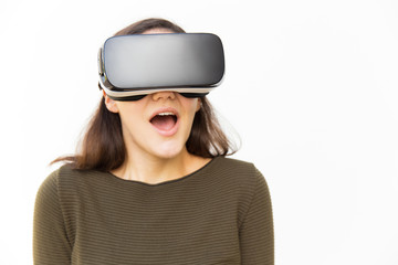Surprised excited student in VR headset shouting or posing with open mouth. Young woman in casual and virtual reality glasses standing isolated over white background. Futuristic technology concept
