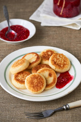 Cottage cheese pancakes with raspberry jam on a white plate 