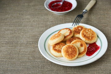 Cottage cheese pancakes with raspberry jam on a white plate 