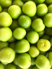 Food background. Top view of a bunch of green cherry plum. Vertical, close-up, cropped shot. Concept of healthy eating.