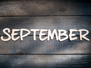 The name of the month is composed of light wooden letters on dark wood. The month of September. 