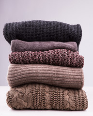 Fototapeta na wymiar A stack of knitted winter sweaters on a white background.