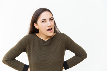 Angry suspicious woman keeping hand on hips and shouting at camera. Young woman in casual standing isolated over white background. Negative emotion or conflict concept