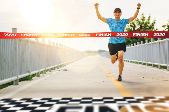 Excited man runner crossing the 2020 finish line of marathon. 2020 success concept.
