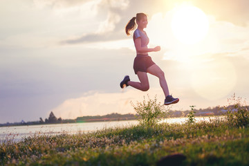 Silhouette of woman trail run sprinting at river side. Fit male fitness runner during outdoor...