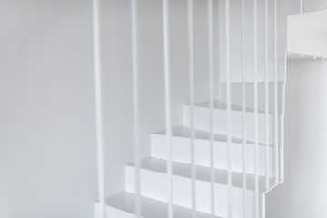 Modern minimalistic metal staircase painted in white with vertical railing, close-up view