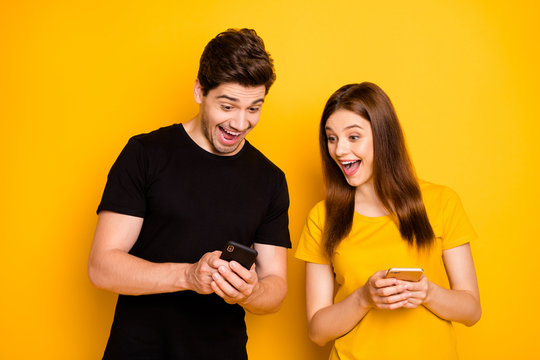 Photo of cheerful excited ecstatic nice overjoyed funky funny couple sharing impressions with each other expressing positive emotions in black yellow t-shirt isolated vivid color background