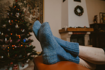 Legs in warm socks lie on leather sofa close-up