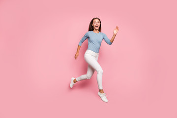 Fototapeta na wymiar Full length body size turned photo of positive trendy casual woman running towards dream in footwear expressing excitement on face isolated pink pastel color background