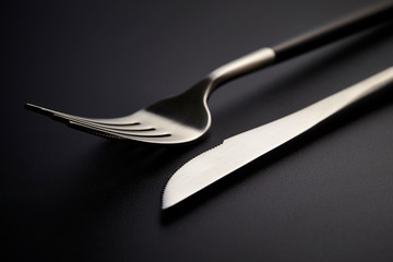 Table fork and knife on black background