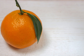 Tangerine with leave on a white wooden background. Copy space.