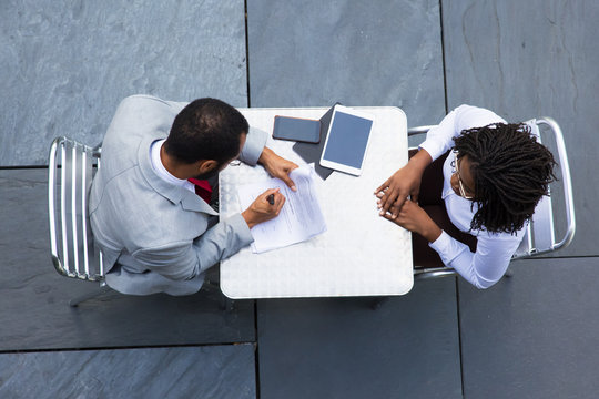 Top view of businessman signing documents. African American woman waiting while her business partner signing official document. Business meeting concept