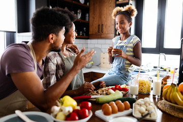 Happy african american family preparing healthy food together in kitchen