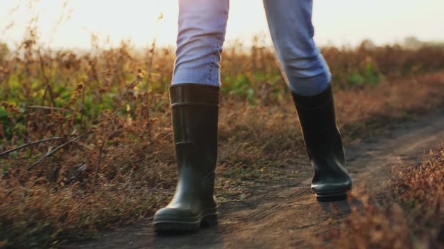 Front view: Man in rubber boots walking down a country road, close-up of legs, slow-motion 4k shot