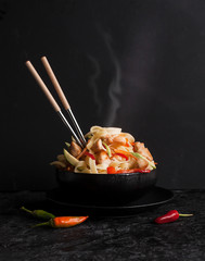 Asian noodles with chicken, vegetables in a bowl, black wooden background. Space for text. Soba noodles, teriyaki chicken, edamame, chopsticks. Dinner in the Asian style. Chinese / Japanese noodles