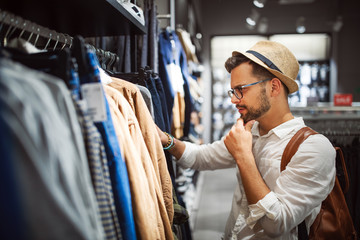 Handsome man shopping for new clothes in store - Powered by Adobe