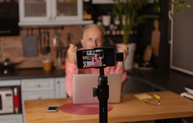 Bearded senior blogger recording video at home.