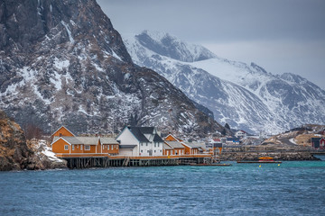 Lofoten Islands, dramatic landscape at sunset. dark clouds over the fishing village, boats and mountain peaks.