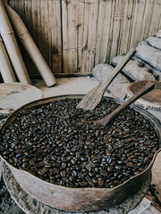 Traditional coffee roasting in metal basin with wooden spoon at hill tribe village in the northern of Thailand..