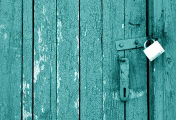Grungy wooden door with lock in cyan tone.