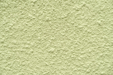 olive painted chipped plaster on the weathered wall. close up view