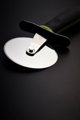 Pizza cutter on black background 