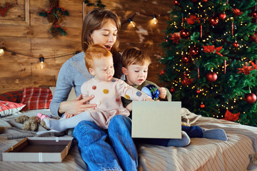 Mother with children watching giftson the bed in Christmas.