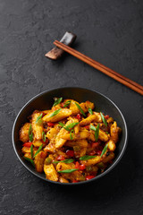 Baby Corn Manchurian dry looks like Schezwan Baby Corn in black bowl at dark slate background. Baby Corn Manchurian - is indo chinese cuisine dish with deep fried corn, bell peppers, sauce and onion.