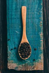 flat lay of black pepper in wooden spoon with copy space
