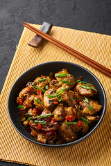 Mushrooms Manchurian dry in black bowl at dark slate background. Mushroom Manchurian - is indo chinese cuisine dish with deep fried mushrooms, bell peppers, sauce and onion.