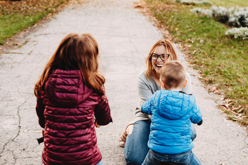 Beautiful young mother laughing while playing outdoor with her kids.