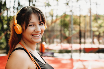 Close up portrait of a lovely young plus size woman looking at camera laughing while listening music doing morning cardio for losing weight.