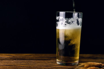 Beer in a glass on a wooden table on a dark background