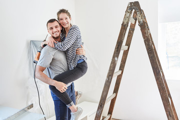 Amorous young couple with drill and ladder
