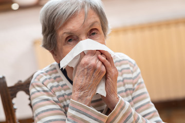 Old woman blowing her nose