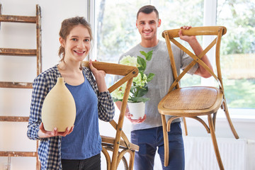Young couple transports furniture and plants