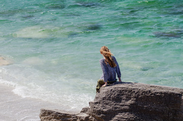 Caspian Sea. The girl on the stone looks at the waves.