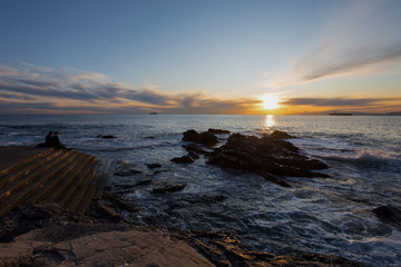 Obraz premium Sitting and looking at sunset with the rough sea, Italy.