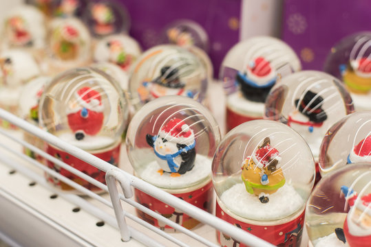 Glass balls with snow with Christmas figures on a store shelf. Showcase with balls with snow.