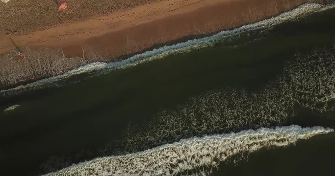 survol de la mer noire vers la plage avec vague sur le sable, parasols blancs et promeneurs et transats