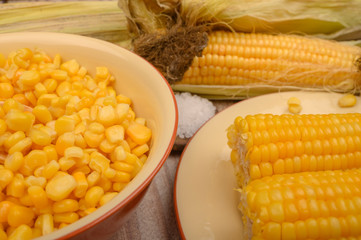 Grains of sweet corn in a plate and ears of corn on the wood table. Healthy diet. Fitness diet. For a sweet treat. Close up.