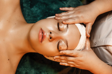 Upper view of a charming woman resting while having skin care routine in a wellness spa center.