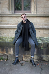 Obraz premium Mann in der Stadt sitzt auf einer Mauer 