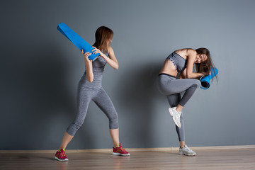 Obraz premium Sporty women fighting twisted blue rugs against gray empty wall