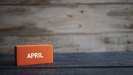 april 5th. Day 5 of month, calendar on a color cubes.  hand puts the day of the month on the name of the month on a wooden background spring, day of the year concept