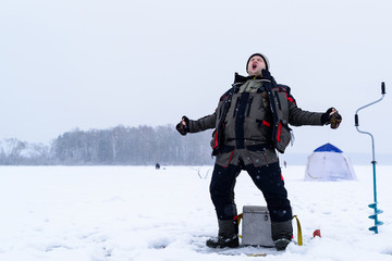 Fototapeta na wymiar Happy shouting adult fisherman after successful winter fishing at cold winter day