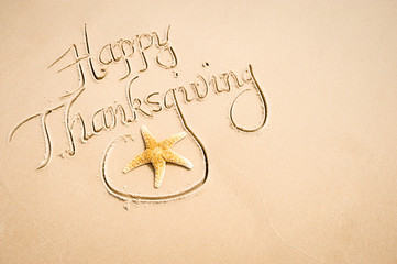 Happy Thanksgiving message with decorative starfish handwritten on smooth sand beach copy space